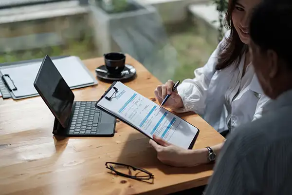 White dentist helping her patient fill out insurance paperwork on a clipboard