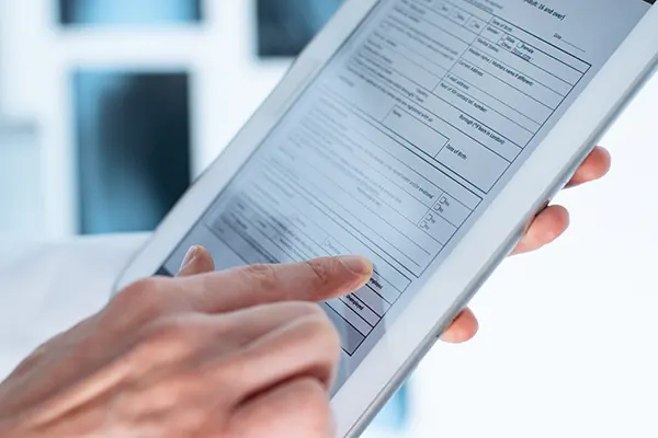 Close up of patient hands filling out patient forms on a tablet device
